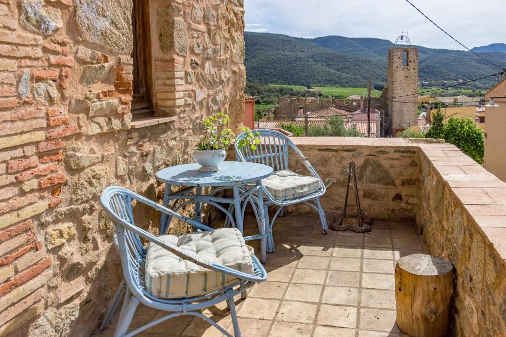 un patio con mesa y sillas en una pared de piedra en Casa de Pedra Casa rural en el Alt Empordà, en Cantallops