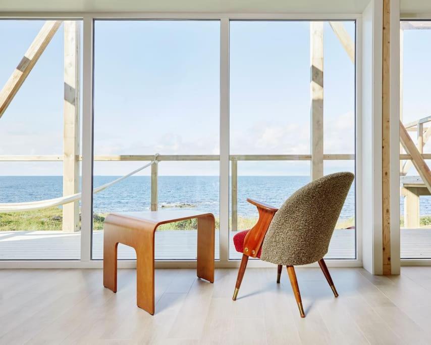 einen Tisch und einen Stuhl in einem Zimmer mit Fenstern in der Unterkunft where the ocean meets land in Ramberg