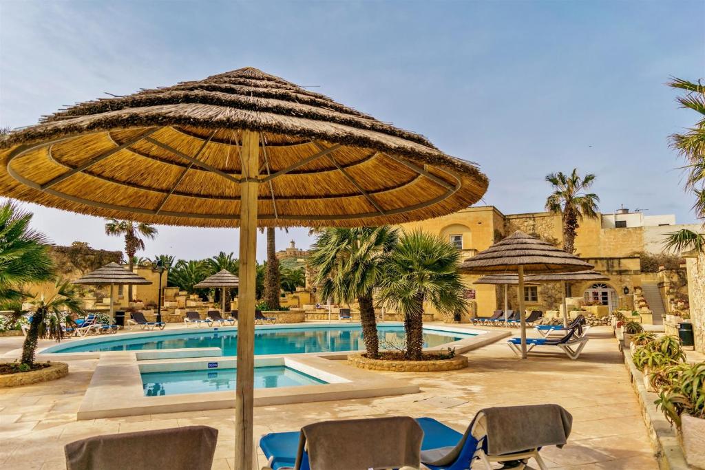 a resort with a pool and an umbrella at Villagg tal-Fanal in Għasri