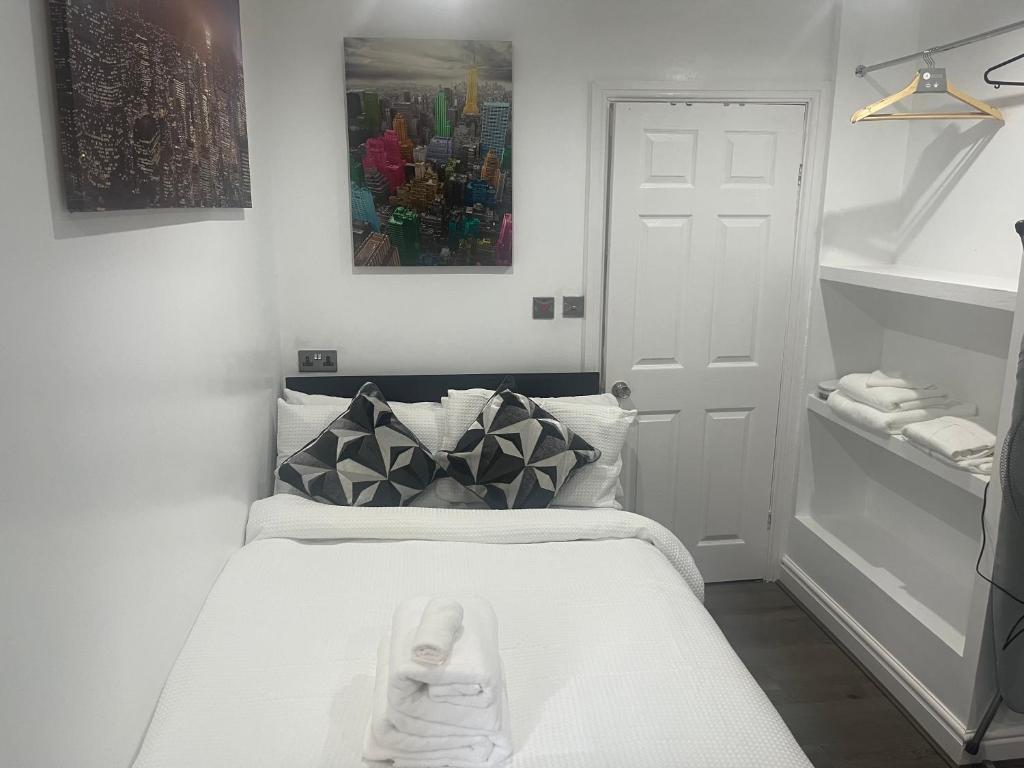 a small white room with a bed and a painting at Dynasty Lodge in Manchester
