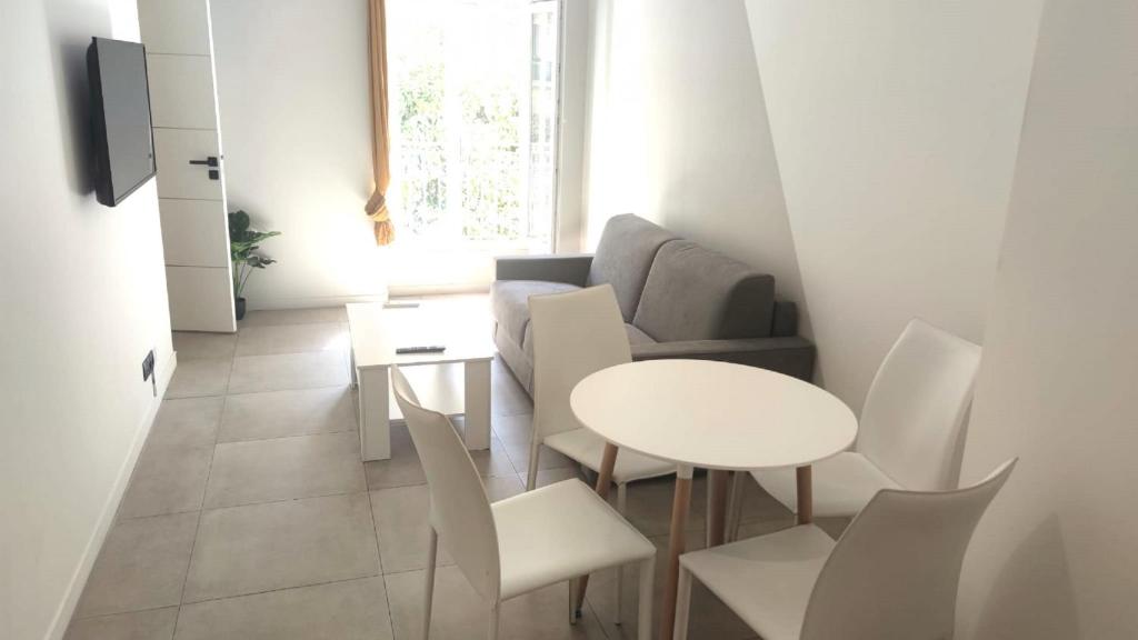 un salon avec une table et des chaises blanches dans l'établissement Baie des anges proche mer 102, à Nice