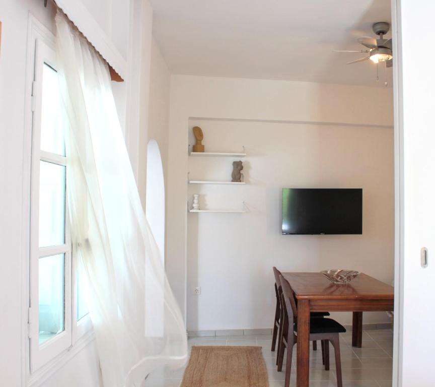 a dining room with a table and a tv on a wall at Lithi Stylish Apartments- Eco Luxury Suite in Tripití