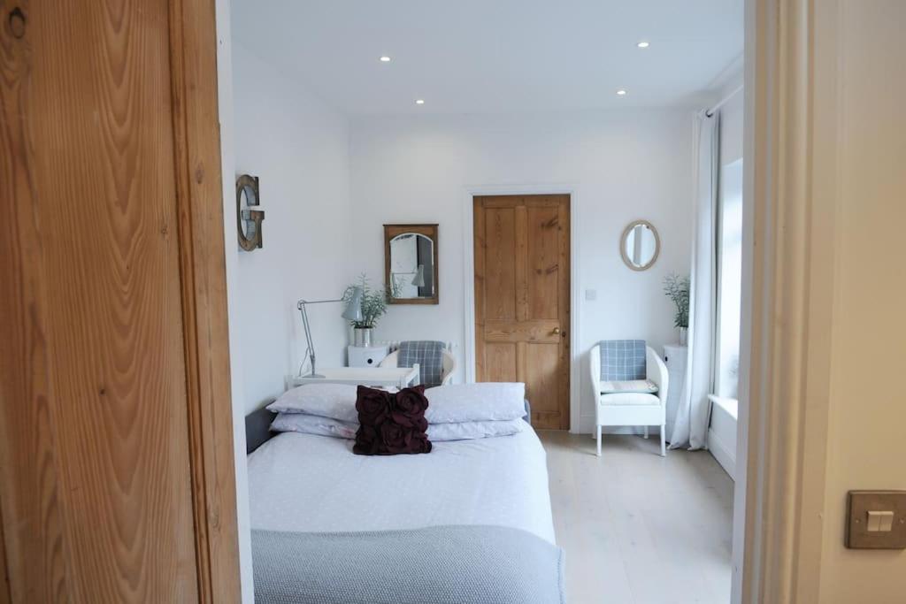 a white bedroom with a bed and a chair at The Snug in Riccall