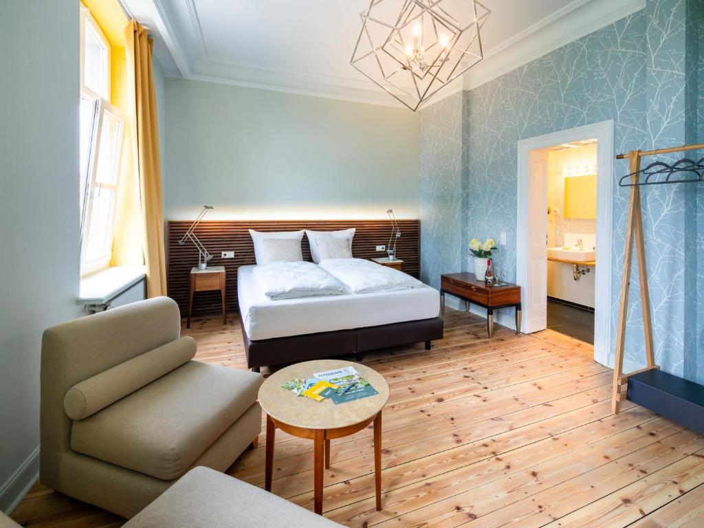 ein Schlafzimmer mit einem Bett, einem Sofa und einem Tisch in der Unterkunft Stuckhotel Fettehenne in Ratingen