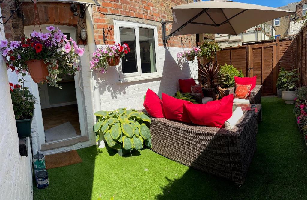 un patio con sillas de mimbre y sombrilla en Self contained Garden Flat newly Refurbished en Bridlington
