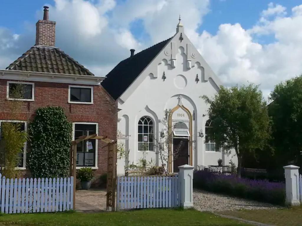 una casa blanca y roja con una valla blanca en Kerkje De Kleine Antonius en Zeerijp