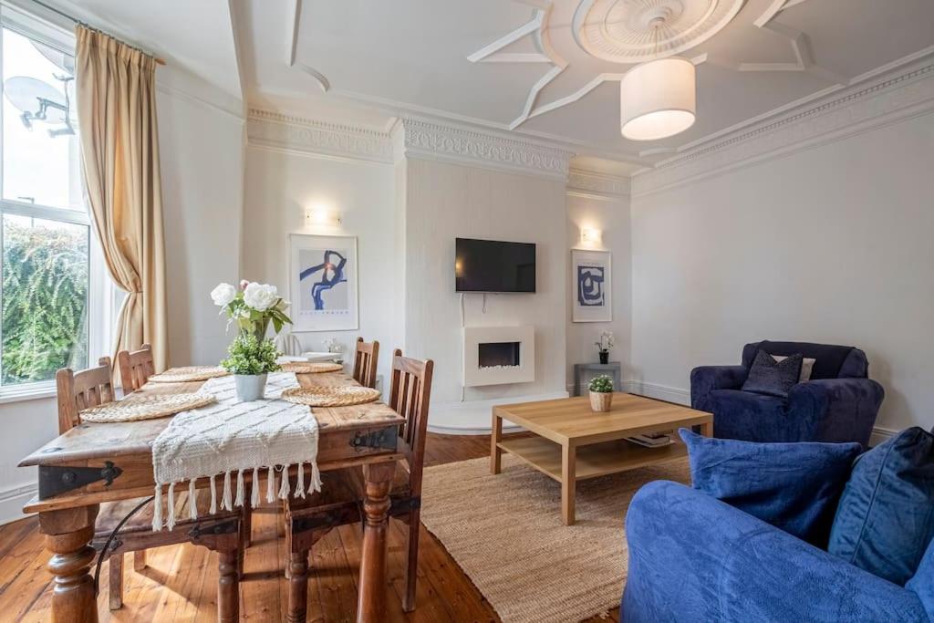 a living room with a table and blue chairs at Spacious Apartment in Jesmond with Parking in Jesmond