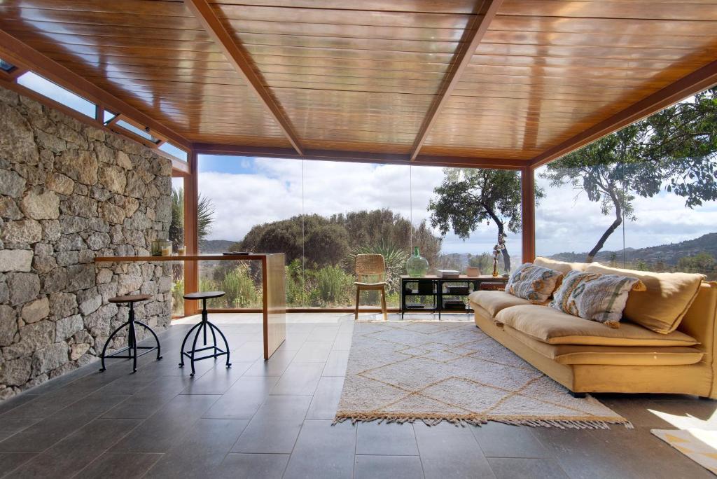 a living room with a couch and a stone wall at La Casita de la Orilla de Peñate in Santa Brígida