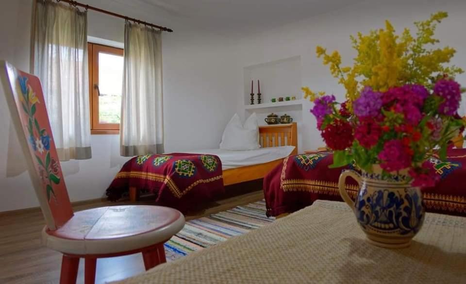 una sala de estar con un jarrón con flores. en Andrada's House Soars, en Şoarş