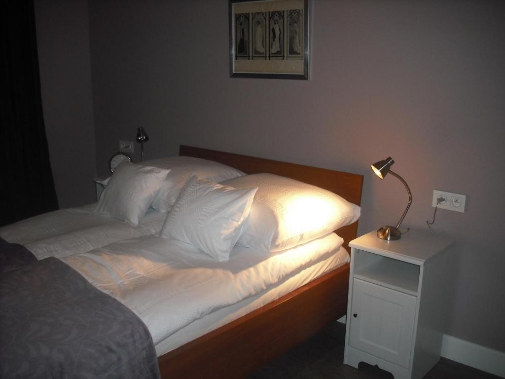 a bed with white pillows and a lamp on a night stand at Apartamenty Algador in Kraków