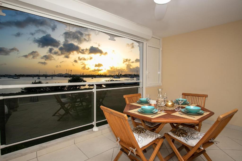 a dining room with a table and chairs and a large window at Coucher de soleil sur le lagon 4 à 5p avec piscine in Marigot