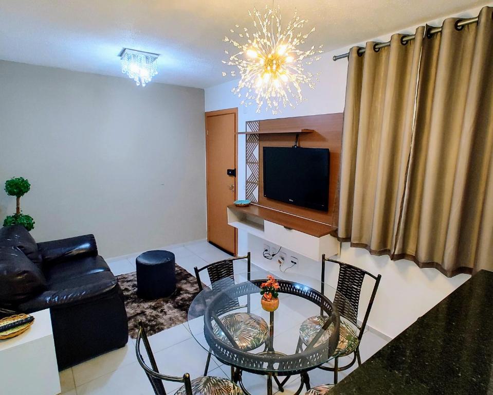 een woonkamer met een tafel en stoelen en een televisie bij Apto Executivo Ravena II in Campo Grande