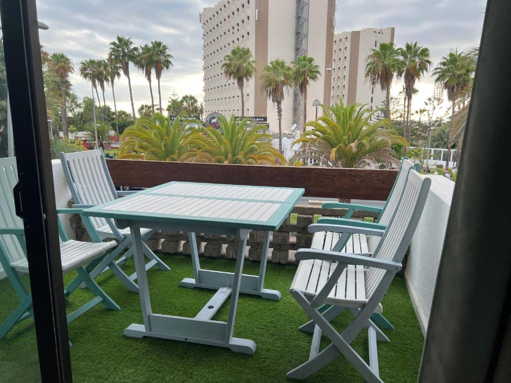 a table and chairs on a balcony with palm trees at Surf Station Tenerife Holiday Apartment Las Americas in Playa de las Americas