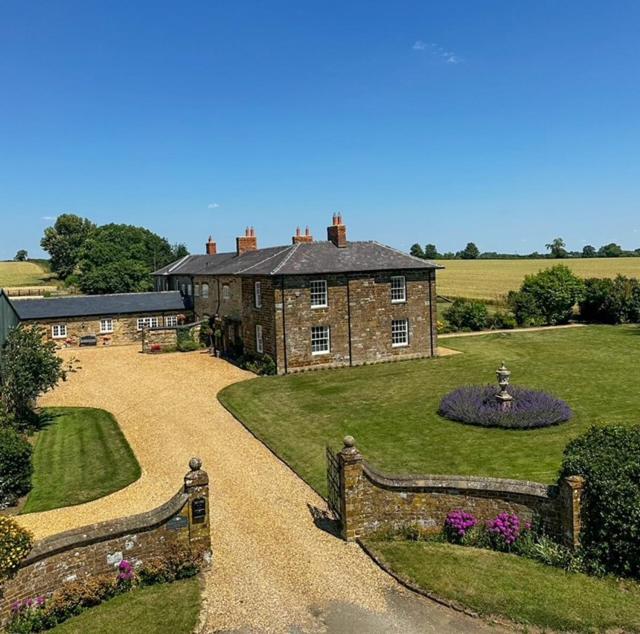 a large brick house with a garden in front of it at Greens Norton House in Towcester