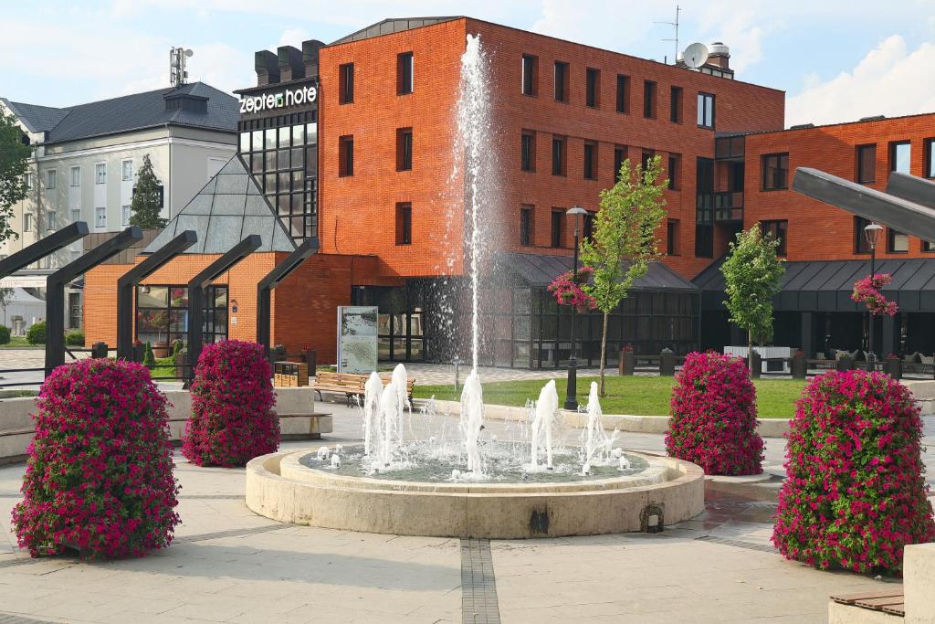 a fountain in a courtyard in front of a building at Zepter Hotel Drina Bajina Basta, member of Zepter Hotels in Bajina Bašta