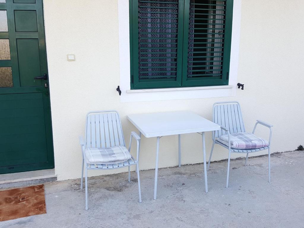 a white table and two chairs next to a building at Apartments Anica in Primošten
