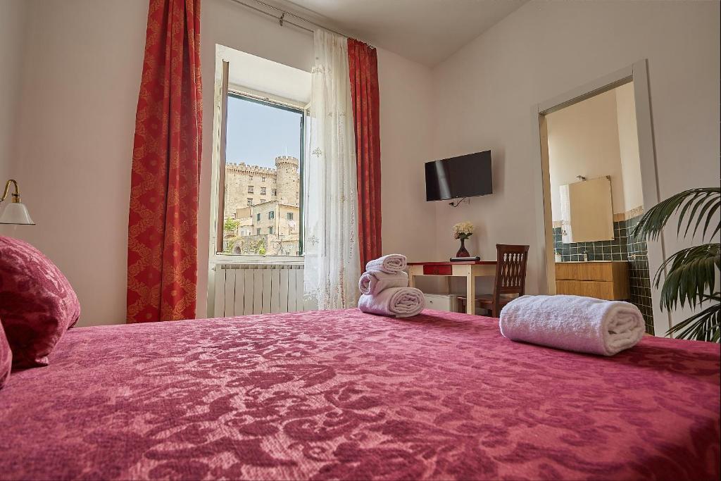 um quarto com uma grande cama rosa e uma grande janela. em LE CAMERE di VITTORIA em Bracciano