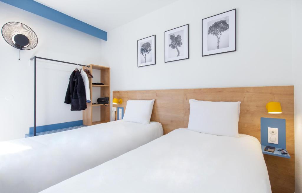 2 camas en una habitación con paredes blancas en Kyriad Marseille Est Aubagne Gémenos, en Gémenos