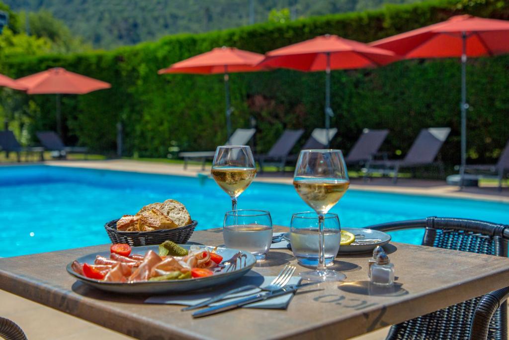 - une table avec de la nourriture et des verres à vin à côté de la piscine dans l&#39;établissement KYRIAD MARSEILLE EST - Aubagne Gémenos, à Gémenos
