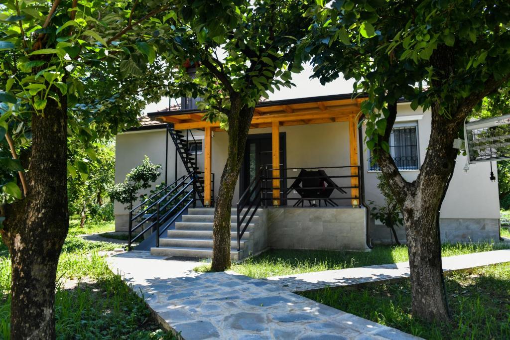 una casa con un porche con árboles en la parte delantera en Nicolaus Hidden Gem Villa en Shkodër