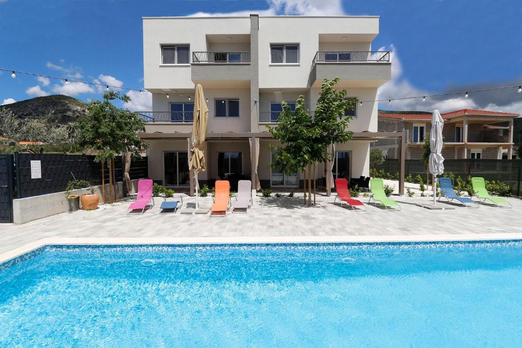 una piscina con sillas y un edificio en Apartments Bulli en Trogir