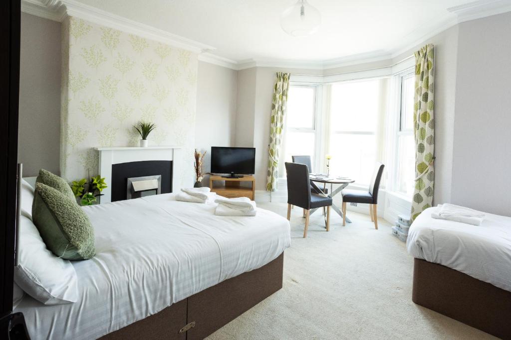 a bedroom with two beds and a table and chairs at The Sea Lynn in Morecambe