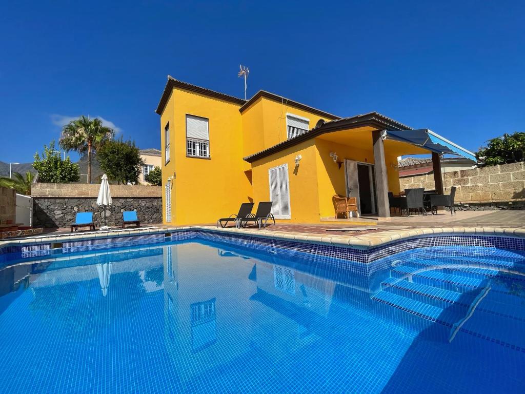 uma piscina em frente a uma casa amarela em Villa Isabel em Adeje