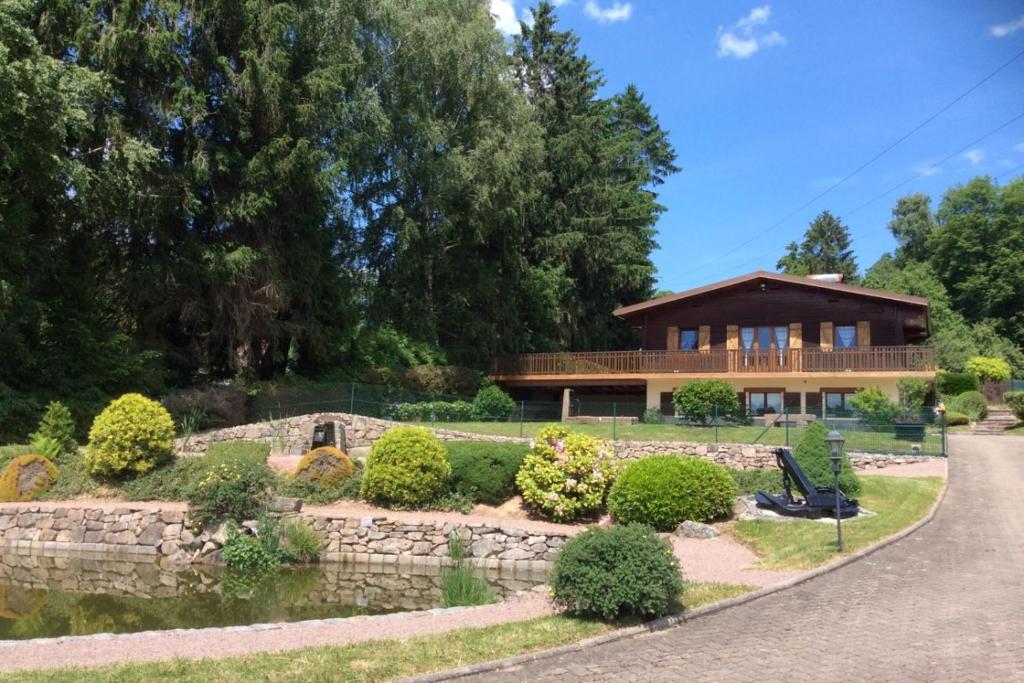 a house with a stone wall in front of a yard at Le Chalet du Cerf au coeur du Massif des Vosges, proche Gérardmer et Alsace in Gerbépal