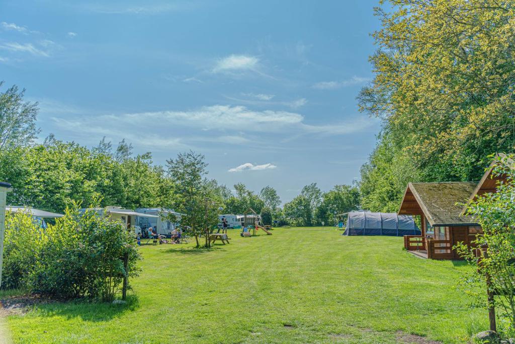 une grande cour herbeuse avec des tentes et des arbres dans l'établissement MiniCamping Drentse Monden, à Nieuw-Weerdinge