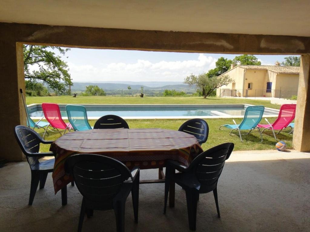 a table and chairs on a porch with a pool at Sur les hauteurs du Luberon in Cucuron