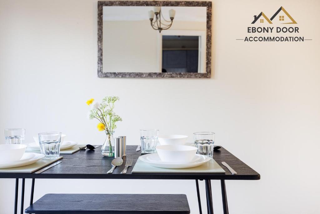 a dining room table with a mirror on the wall at Ebony Door Accommodation Charming 3 Bedroom House Thurrock Sleeps 6 in Grays Thurrock