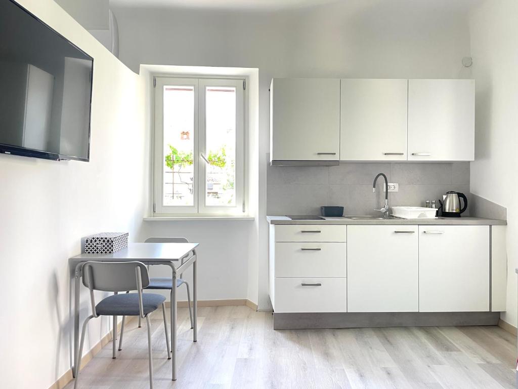 una cucina con armadi bianchi, tavolo e finestra di Koper Relax home a Capodistria
