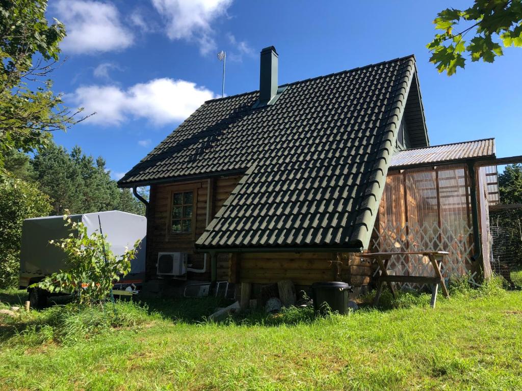 a log cabin with a roof on a grass field at Juniper holiday house in Kassari with sauna in Hiiumaa