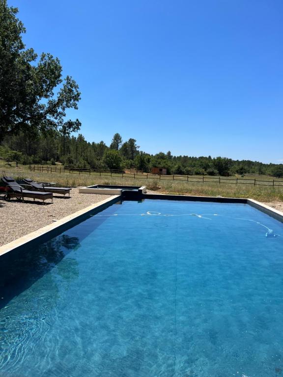 una gran piscina de agua azul en un campo en charmant appartement indépendant au sein d'un mas provençal en Aups