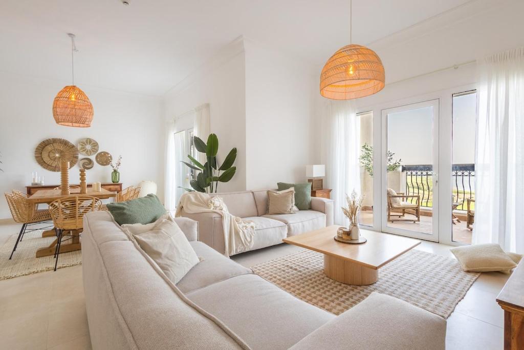 a white living room with a couch and a table at Voyage Ansam Three Bedroom With Ocean Views in Abu Dhabi