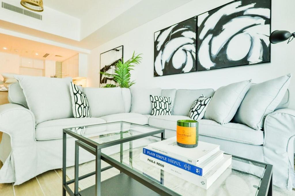 uma sala de estar com um sofá branco e uma mesa de vidro em Voyage One Bedroom In Mayan em Abu Dhabi