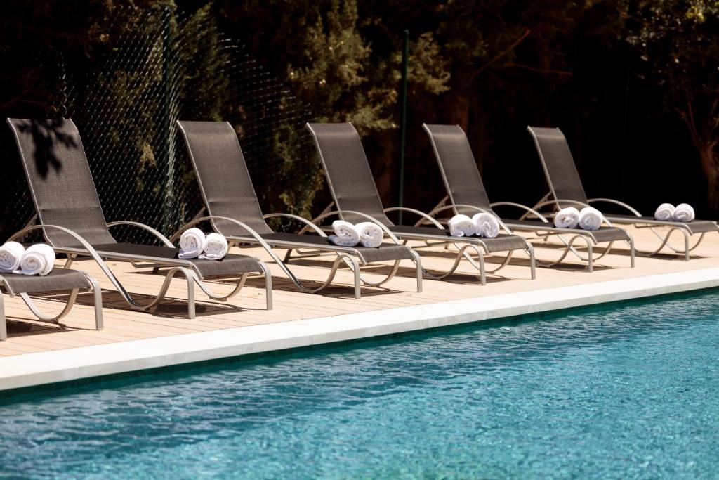 a row of lounge chairs next to a swimming pool at Hotel Pax Guadalajara in Guadalajara