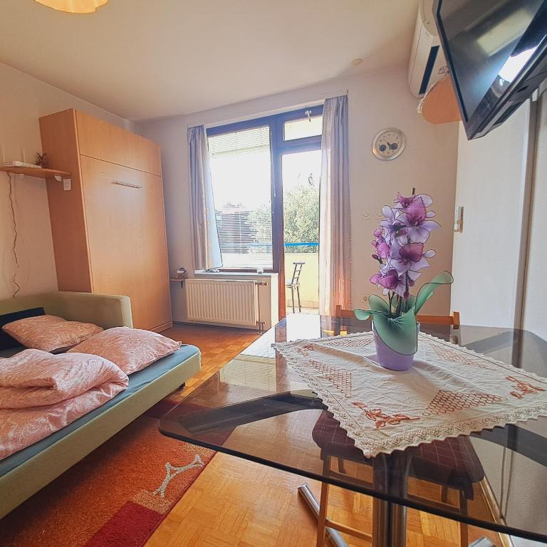 a living room with a table with a vase of flowers on it at Blaško apartment in Izola