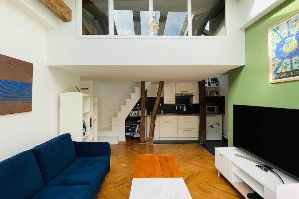 un salon avec un canapé bleu et une télévision dans l'établissement Bright duplex on the top floor - close to Opera, à Paris