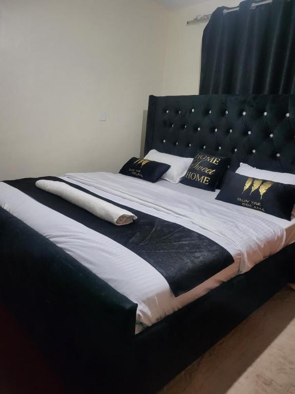 a bed with a black headboard and pillows on it at G&G Executive ONE bedroom Ngala Nakuru in Nakuru