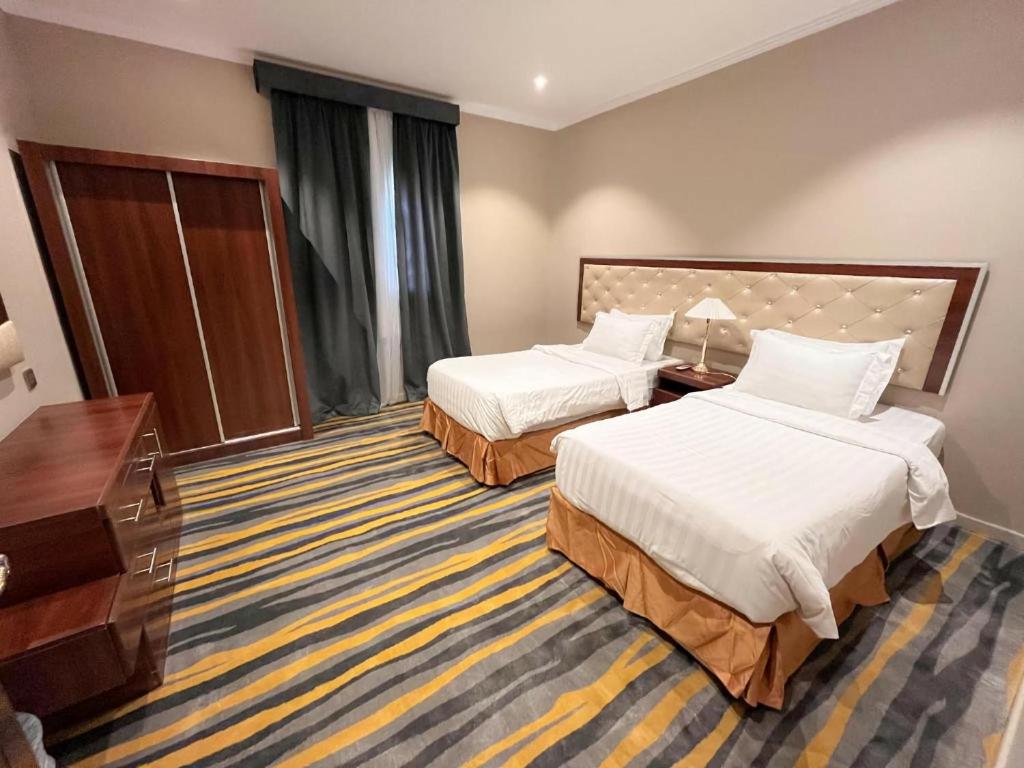 a hotel room with two beds and a desk at رمال الجزيره in Al Ḩawīyah