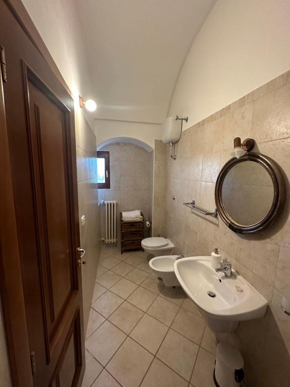 y baño con 2 aseos, lavamanos y espejo. en Torre Marinella, en Ostuni