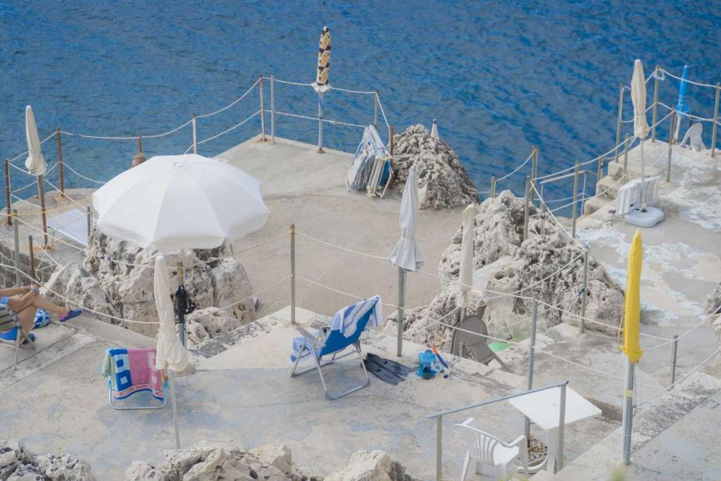 una sombrilla y sillas en una playa junto al agua en Sea House on the rocks, en Santa Cesarea Terme