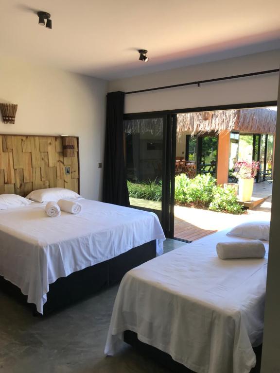 1 dormitorio con 2 camas y ventana grande en Barong EcoVilla, en Barra Grande