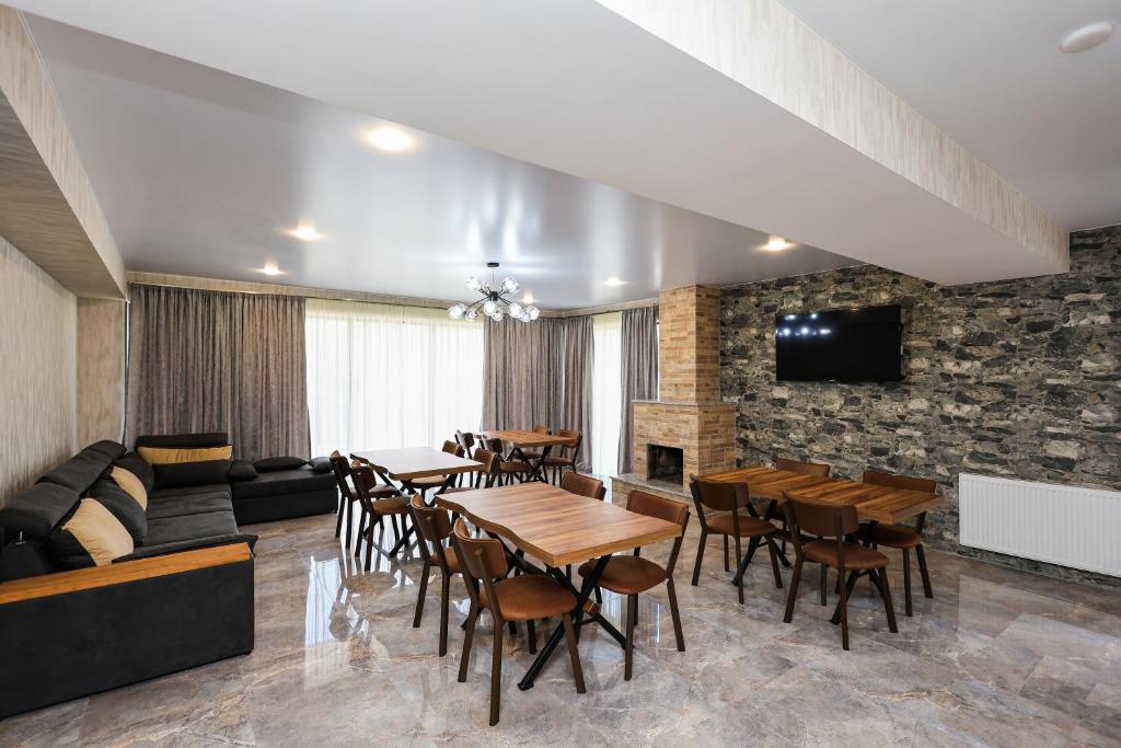 a dining room with tables and chairs and a stone wall at Heaven Hill in Stepantsminda