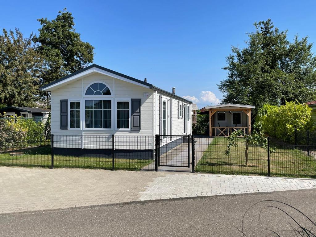 una casa blanca con una valla delante en De Roos chalet 174, en Sint Annaland