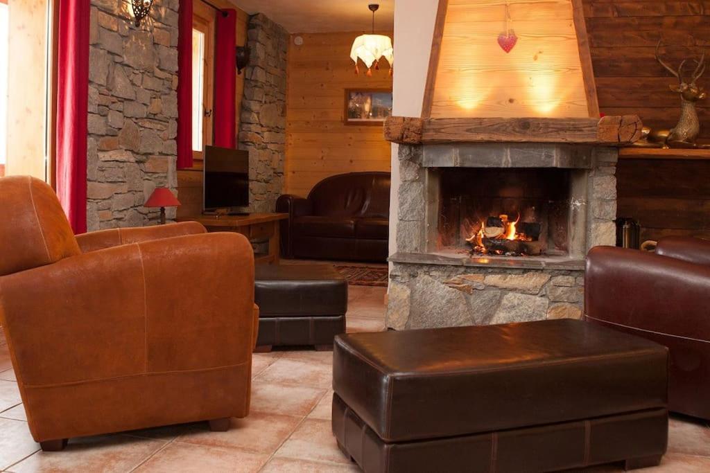 un salon avec cheminée et meubles en cuir dans l'établissement Montseti - 3 bedroom ski-in ski-out apartment, à Sainte-Foy-Tarentaise