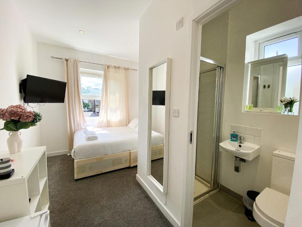 a bedroom with a bed and a sink and a mirror at Wembar Hotel in London