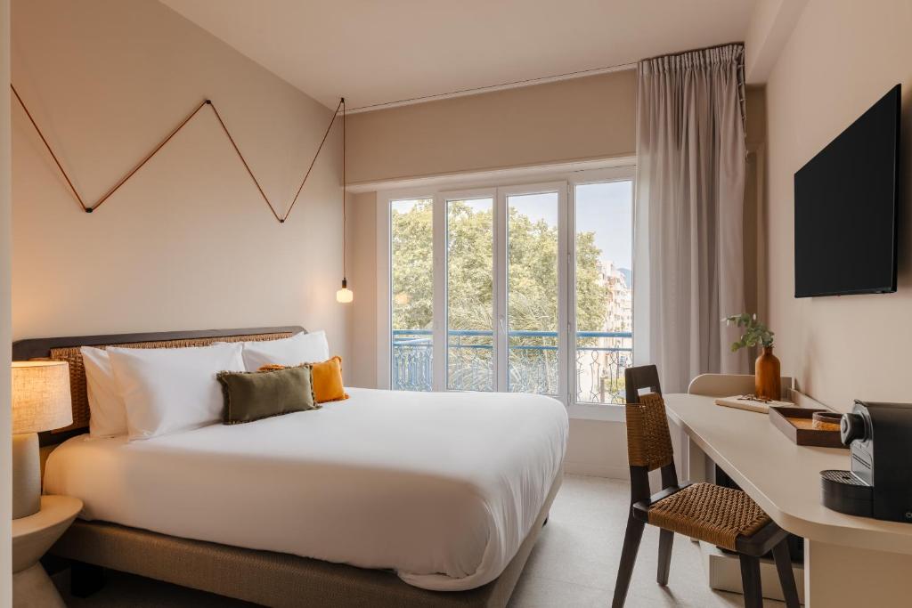 ニースにあるYelo Promenade powered by Sonderのベッド、デスク、窓が備わるホテルルームです。