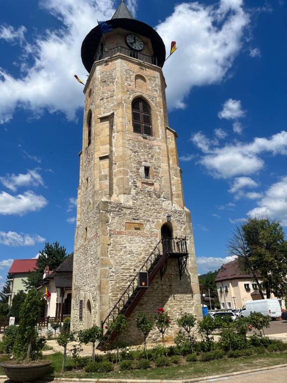 Una torre de piedra alta con un reloj. en Cazare David si familia ., en Piatra Neamţ